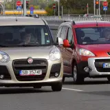 Złoty Fiat i czerwony Peugeot jadące po drodze.
