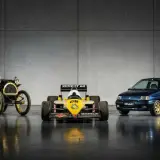 Trzy samochody Renault: zabytkowy, bolid F1 i współczesny, na tle szarej ściany.