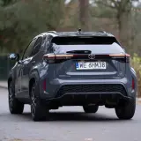 Szary Toyota Yaris Cross hybrydowy z tyłu na drodze.