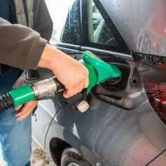 Ręka wlewa paliwo do baku samochodu.