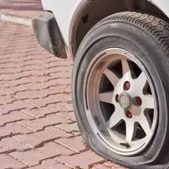 Płaska opona samochodu na felgi na czerwonej kostce brukowej.