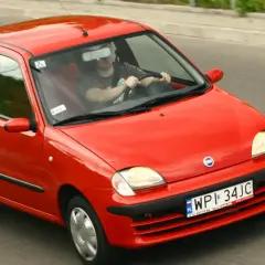 Czerwone Fiat Seicento w ruchu drogowym, widok z przodu i z boku.