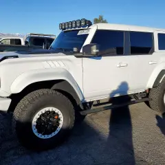 Biały Ford Bronco z USA, z dodatkowym oświetleniem na dachu i terenowymi oponami.