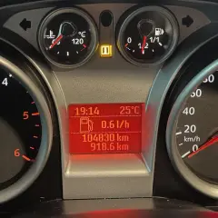Deska rozdzielcza Ford Focus z kontrolkami: temperatura, paliwo, przebieg, prędkościomierz i kontrolka hamulca ręcznego.
