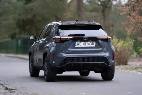 Szary Toyota Yaris Cross hybrydowy z tyłu na drodze.