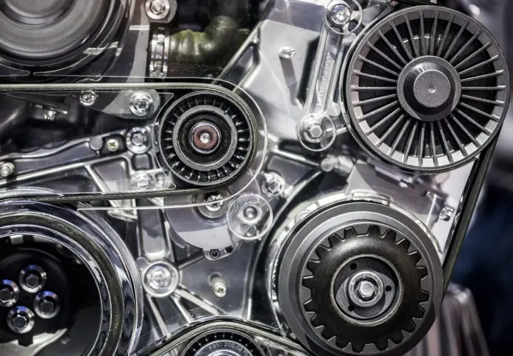 Zbliżenie na mechanizm silnika samochodowego z paskami i kołami pasowymi.