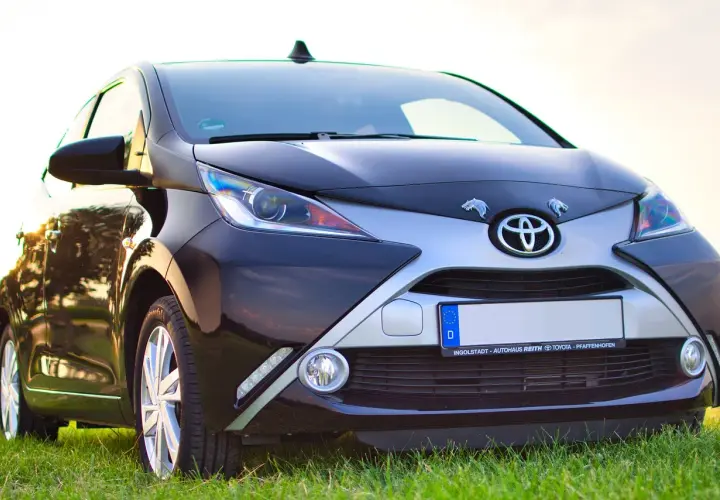 Czarny samochód Toyota z przodu, na tle trawy i nieba.