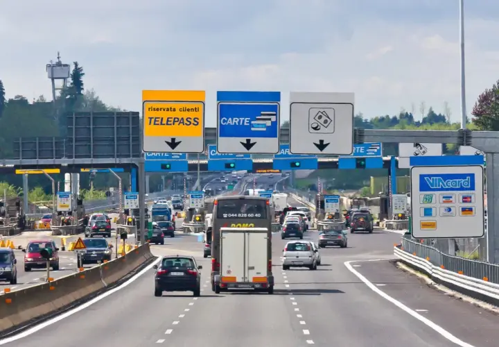 Autostrada we Włoszech z bramkami opłat, znakami Telepass i Carte, oraz samochodami w ruchu.