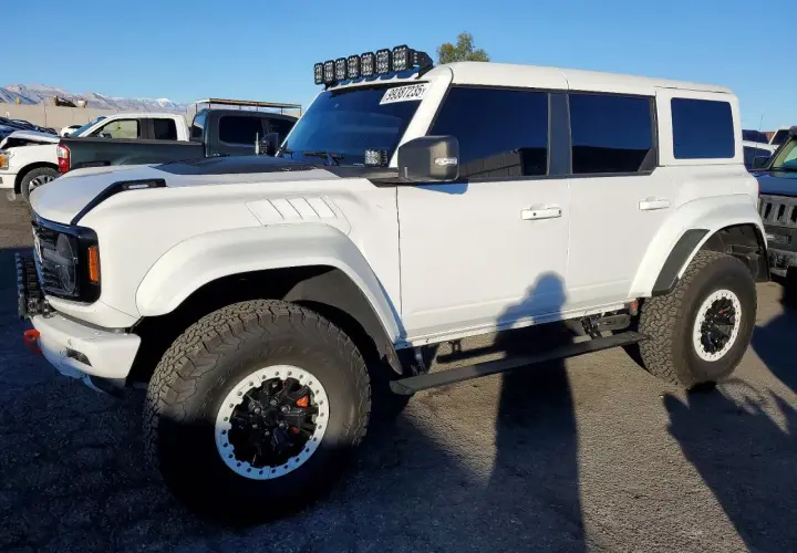 Biały Ford Bronco z USA, z dodatkowym oświetleniem na dachu i terenowymi oponami.