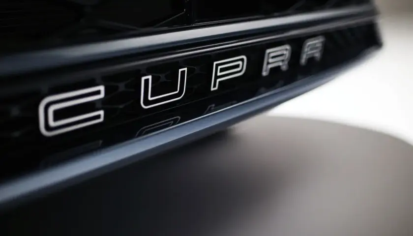 Napis CUPRA na czarnym grillu samochodu.