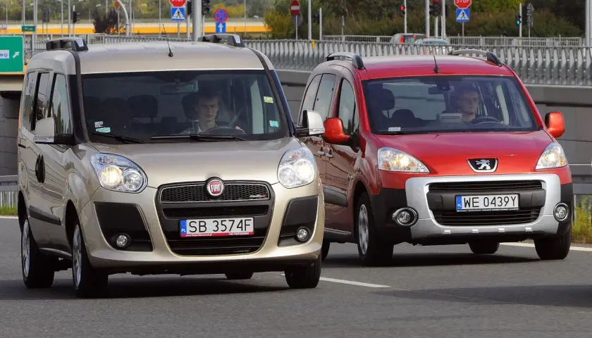 Złoty Fiat i czerwony Peugeot jadące po drodze.