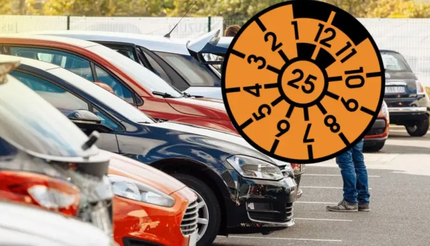 Rząd samochodów na parkingu z pomarańczową tarczą z numerami i cyfrą 25.