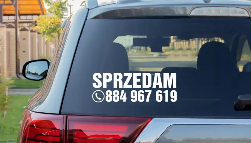 Nalepka na szybę samochodu z napisem "SPRZEDAM" i numerem telefonu.