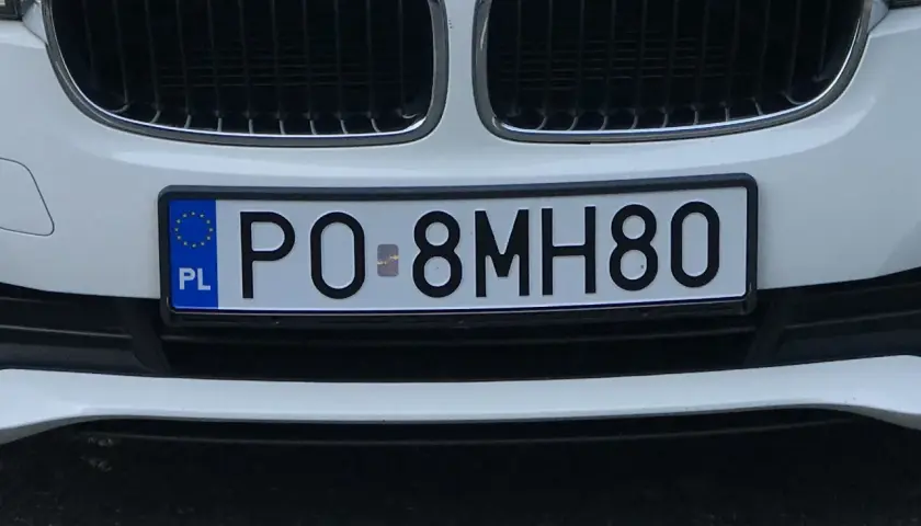 Zbliżenie na polską tablicę rejestracyjną samochodu z numerem PO 8MH80.