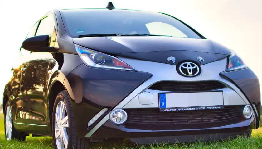 Czarny samochód Toyota z przodu, na tle trawy i nieba.