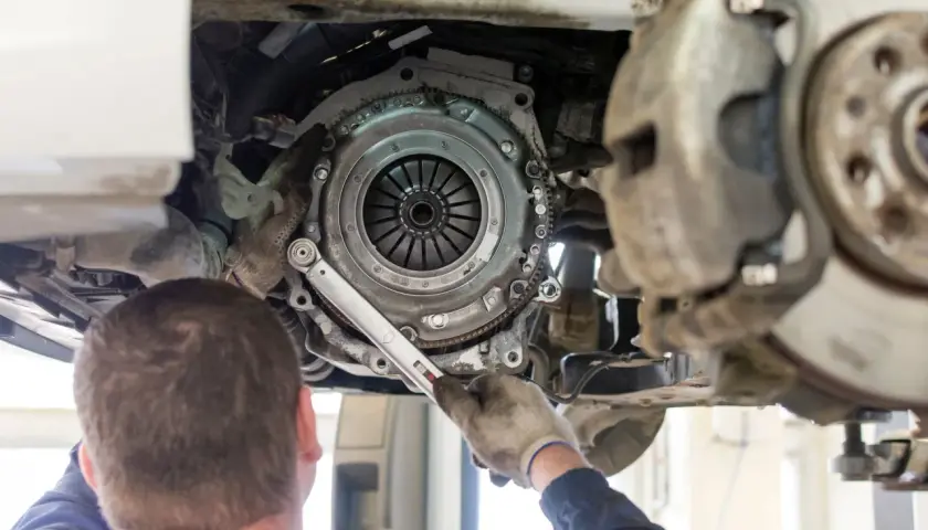 Mechanik wymieniający sprzęgło w samochodzie VW Passat.