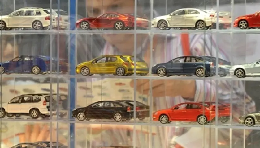 Modeliki samochodów w gablotach: białe kombi, czerwony sportowy, żółty hatchback, granatowy sedan, srebrny coupe.