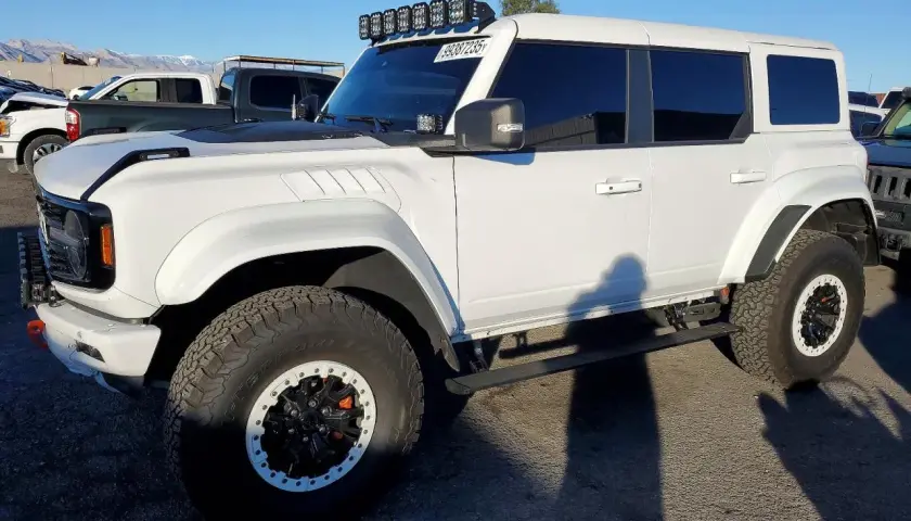 Biały Ford Bronco z USA, z dodatkowym oświetleniem na dachu i terenowymi oponami.