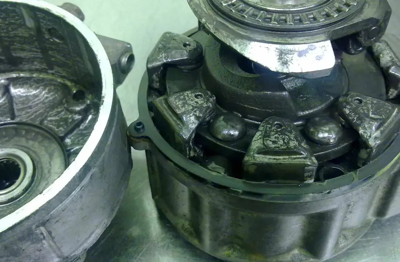 Rozłożone sprzęgło elektromagnetyczne klimatyzacji z widocznymi elementami mechanicznymi.
