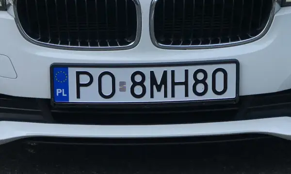 Zbliżenie na polską tablicę rejestracyjną samochodu z numerem PO 8MH80.